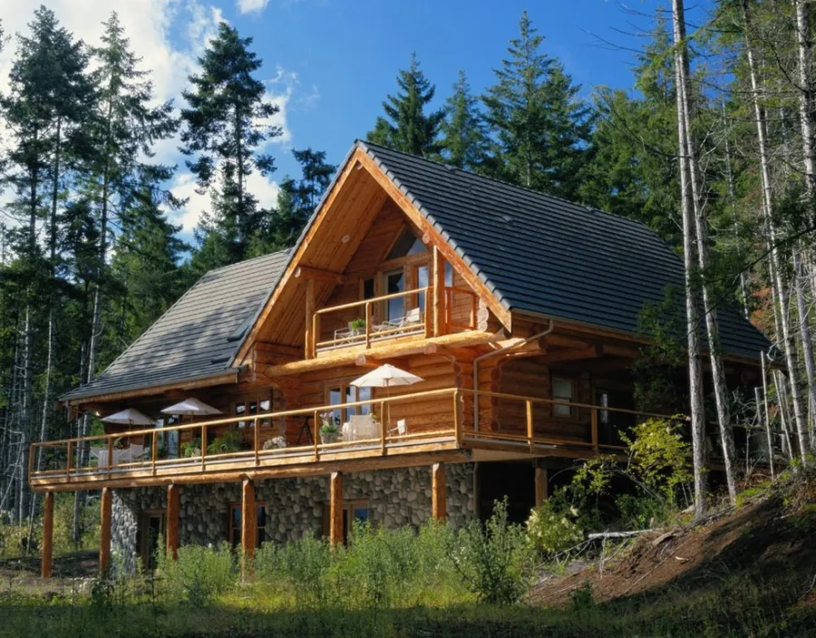 The exterior of a three story log cabin with wrap around deck and balcony above