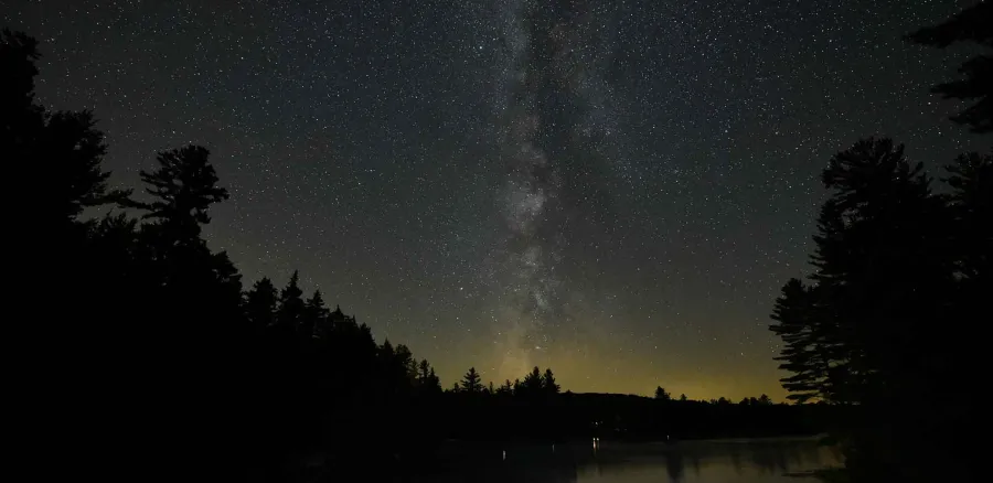 The glorious milky way seen through dark skies over the lake and surrounding pines