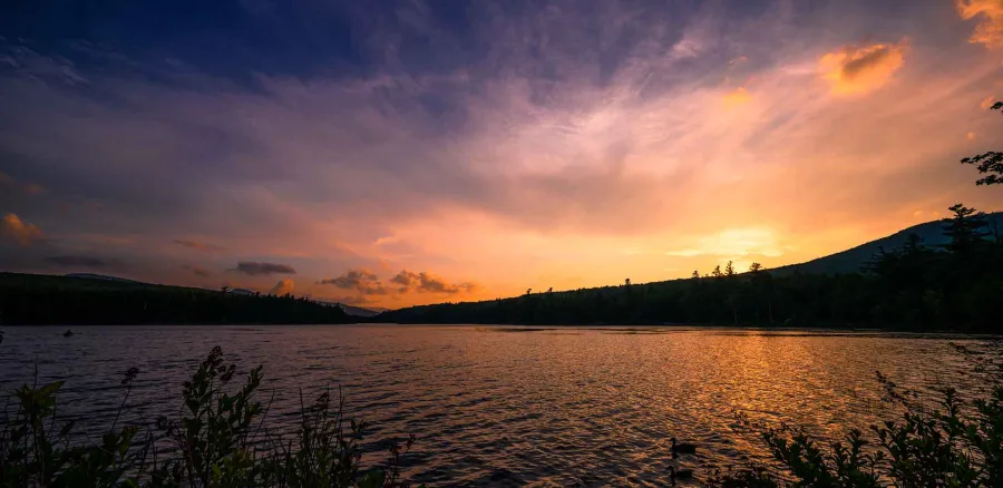 Gorgeous sunset of golden light into violets and deep purples over the gentle waves of a lake